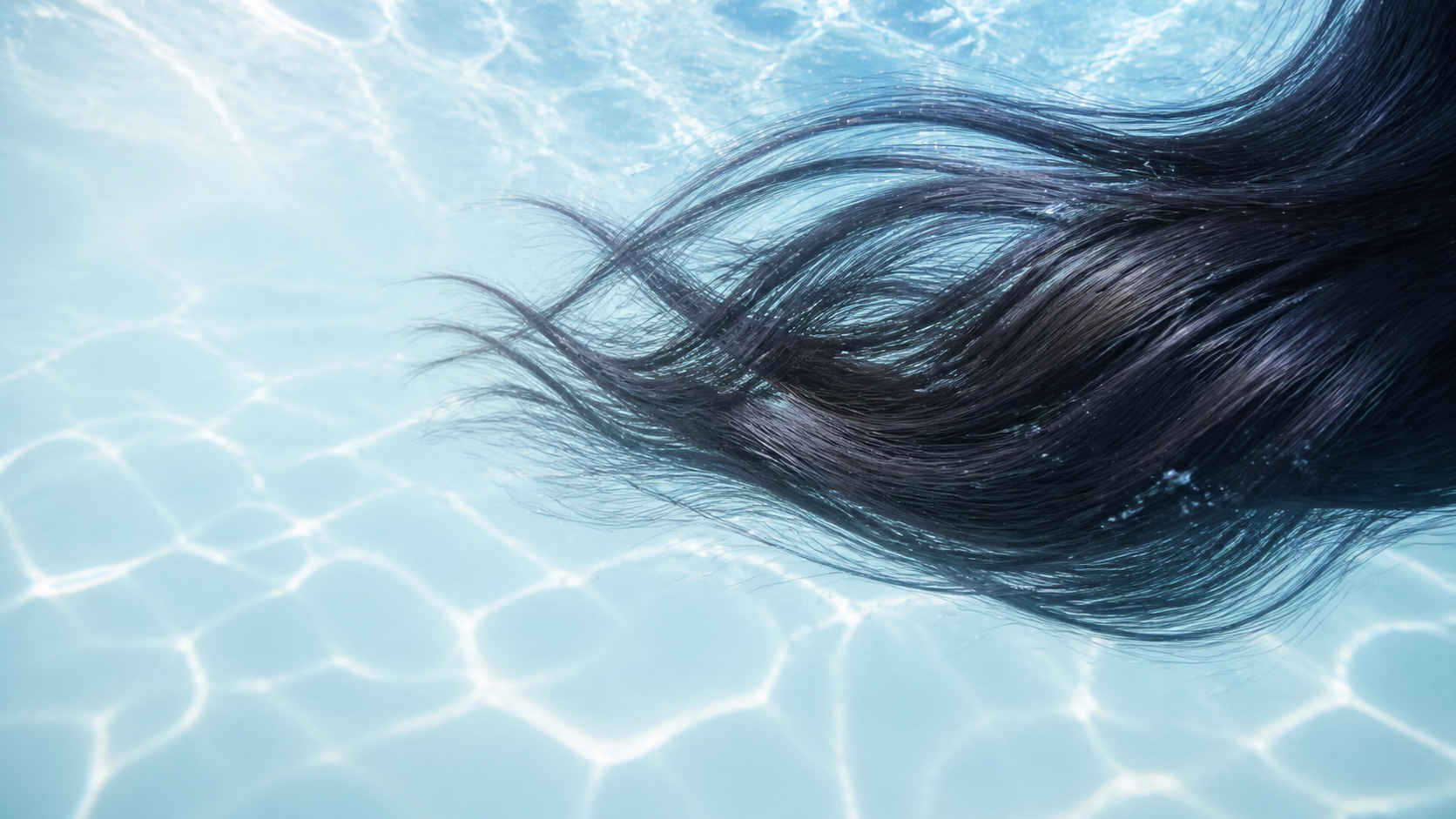 Healthy dark hair flowing through clear blue water